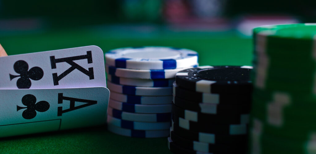 poker player peeks at ace-king of clubs next to some poker chips